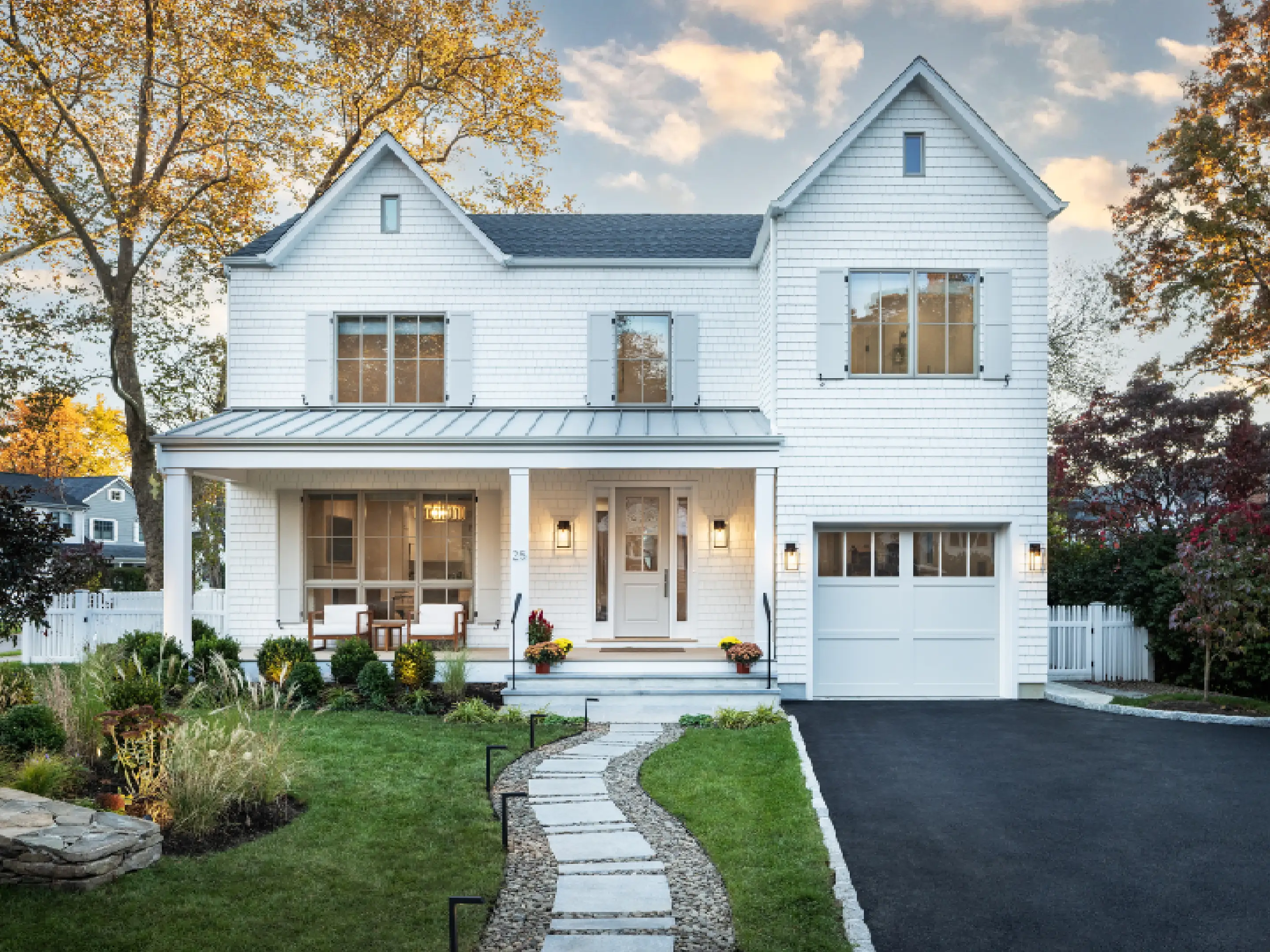 A charming white two-story house with a front porch and manicured lawn.