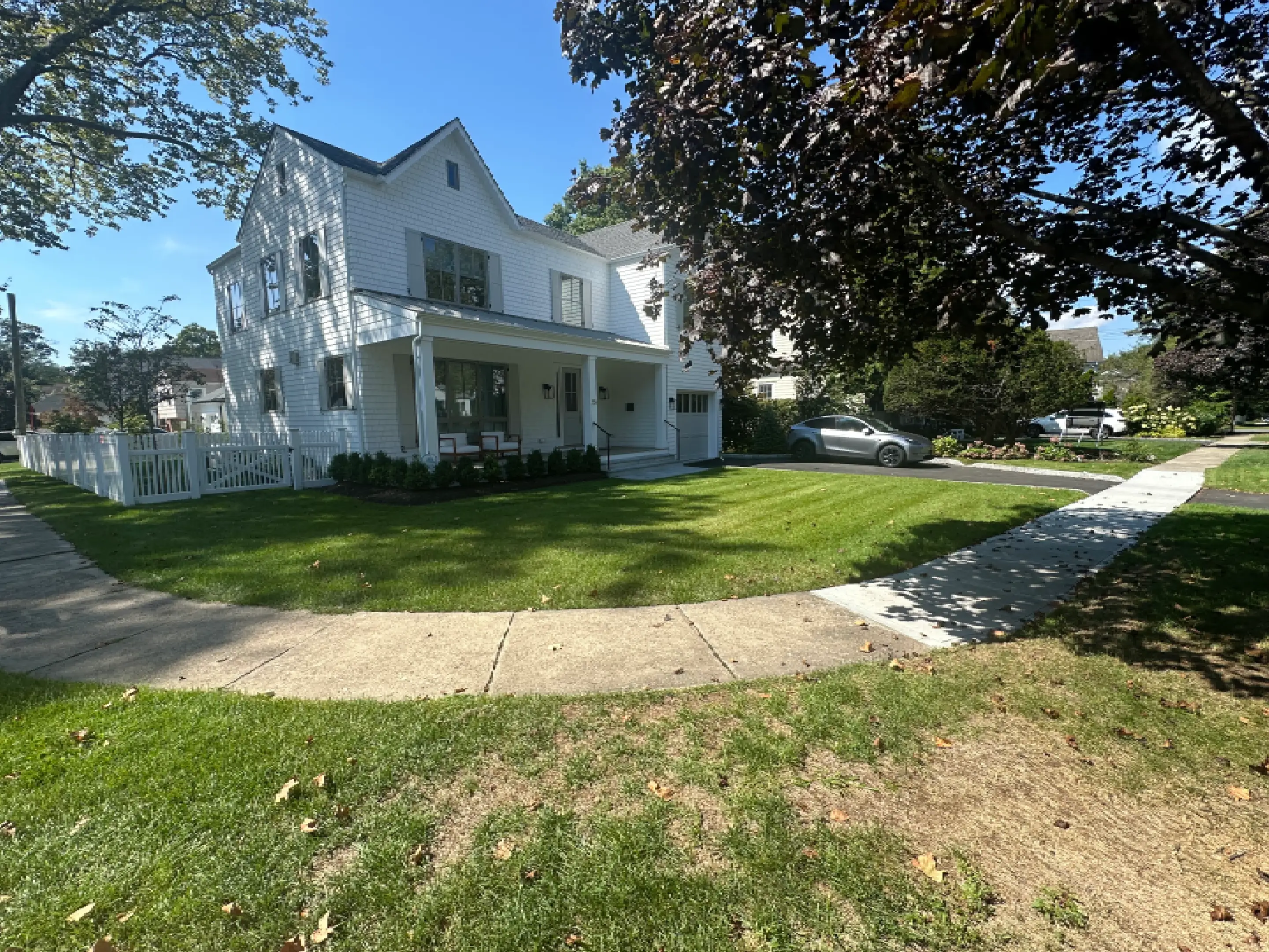 A white two-story house with a porch and a curved sidewalk.