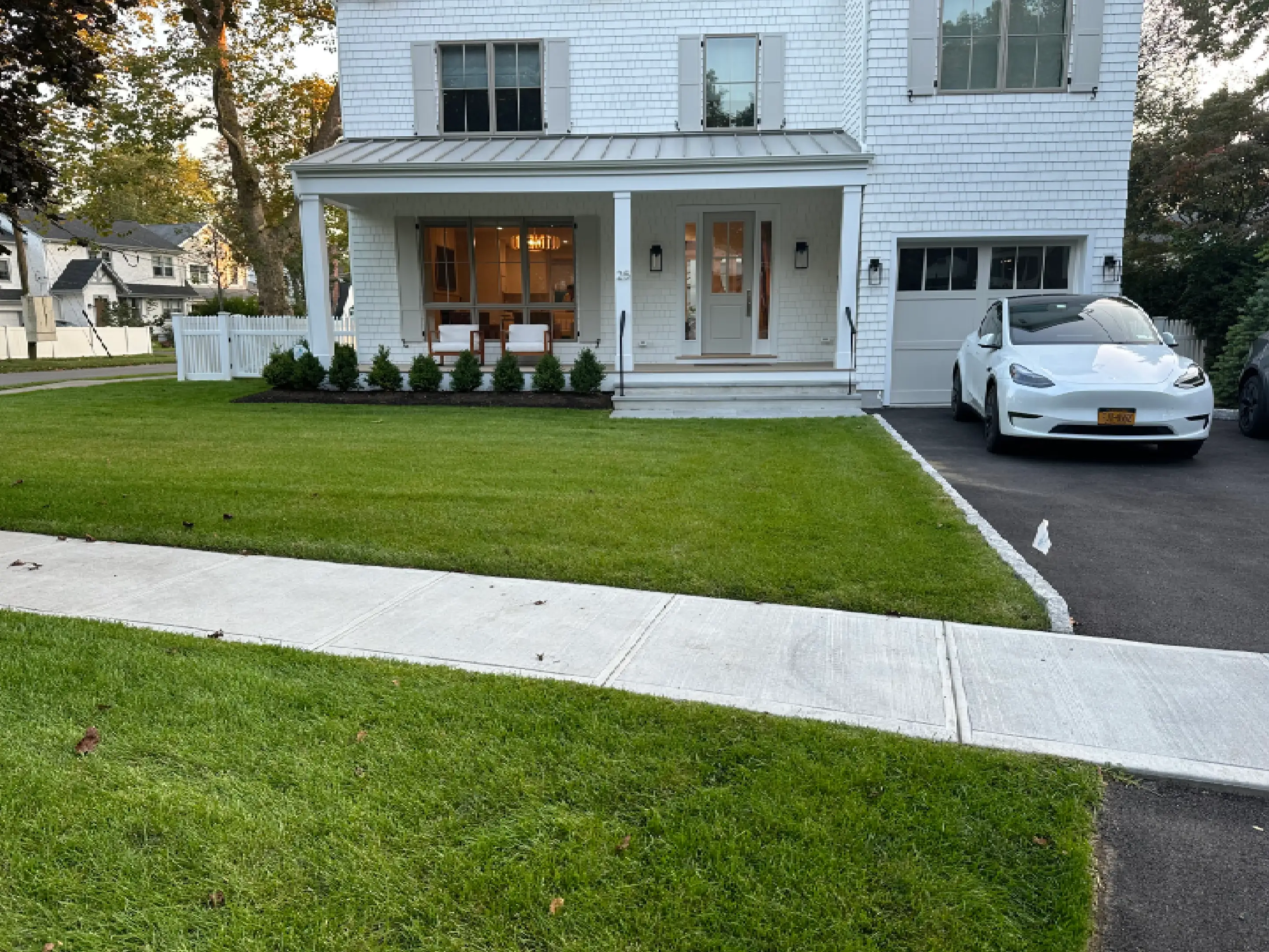 Modern white house with a neatly trimmed lawn and a clean sidewalk.