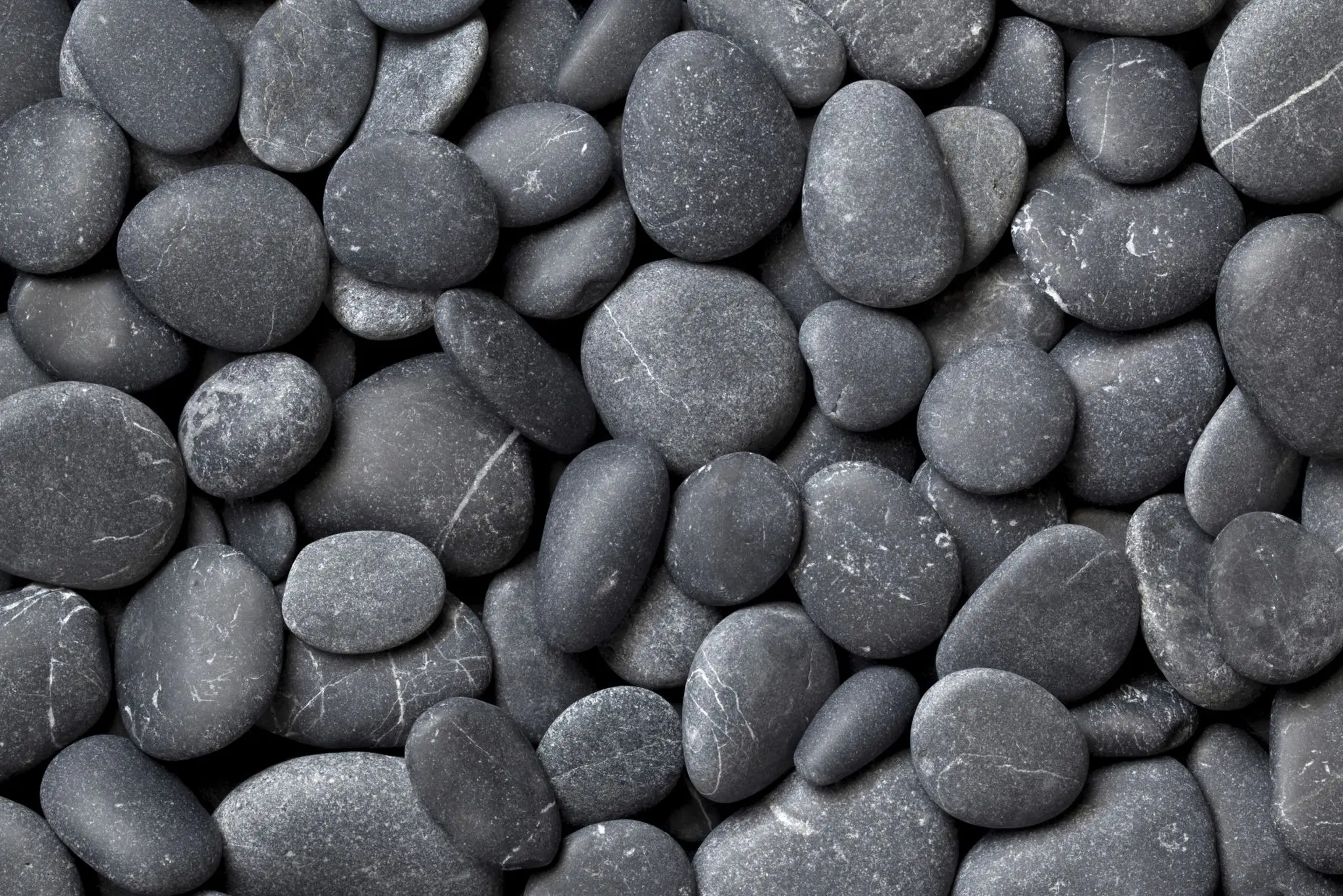 Smooth black river stones closely packed together.