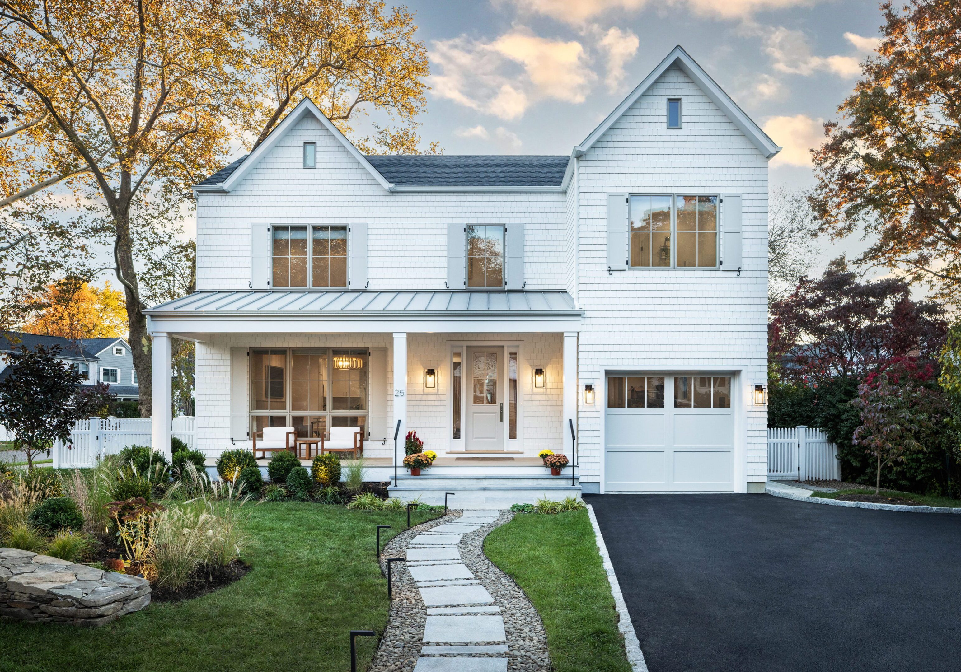 Elegant white two-story house with a cozy front porch and well-kept garden.